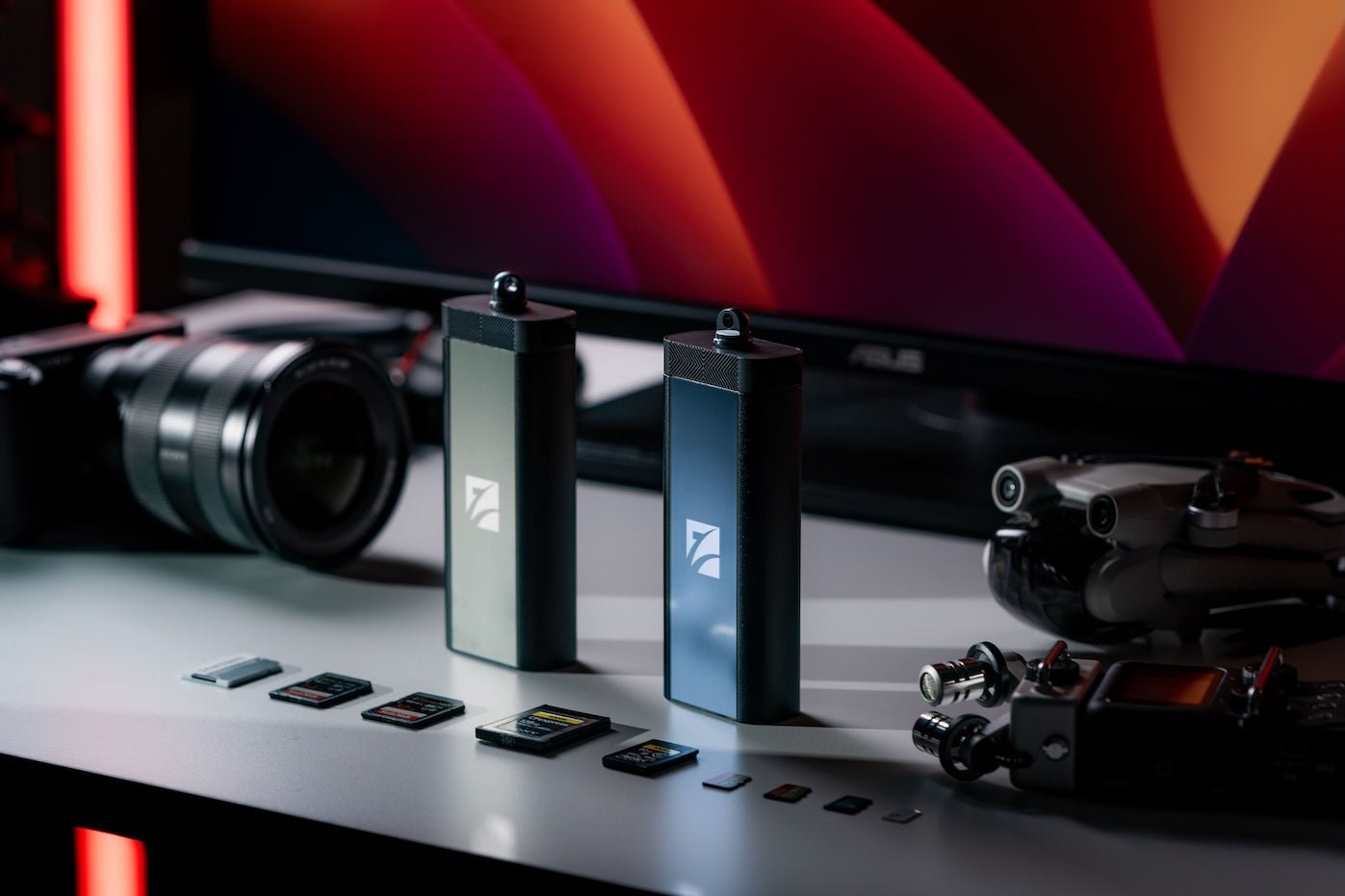 Freewell multi card reader and a set of SD cards displayed on a desk, with a camera, drone in the background.