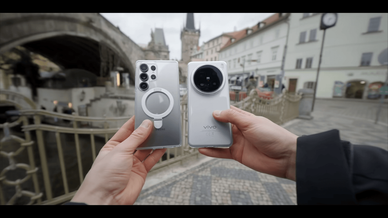The Samsung S25 Ultra and Vivo X200 Pro smartphones are held side by side in front of a historical building.