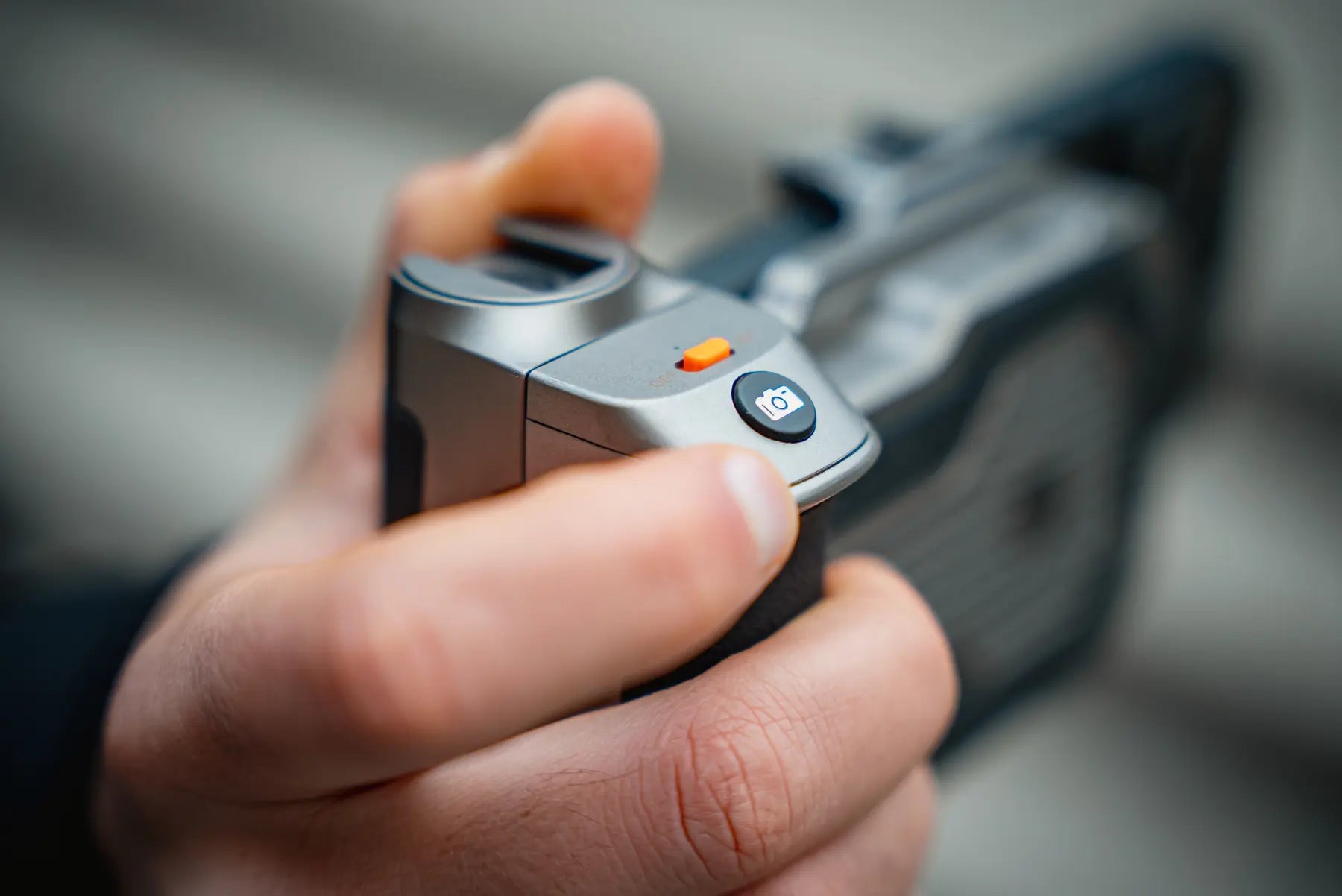Thumb pressing the camera button on the Pro SSD Hub Bluetooth remote