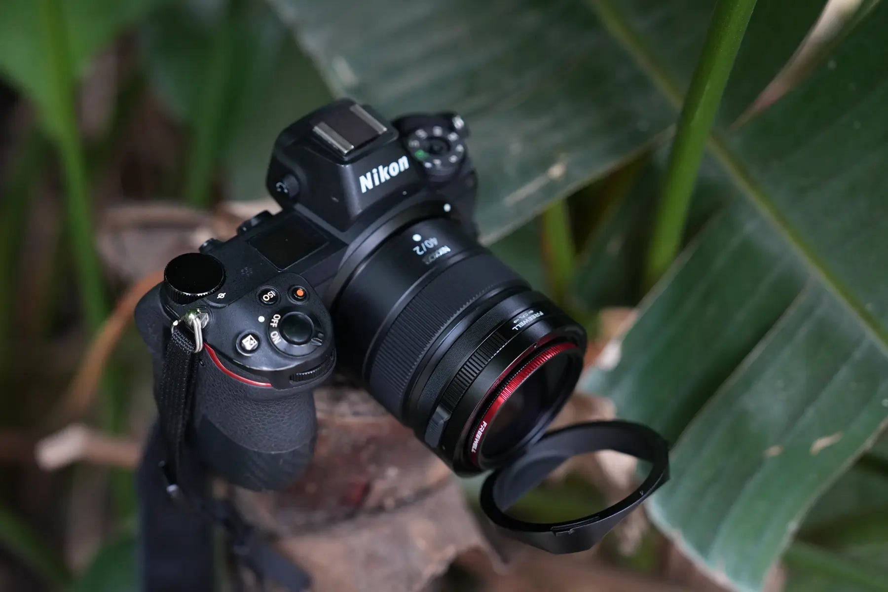 Nikon camera with Freewell Real Lens Hood placed among green leaves