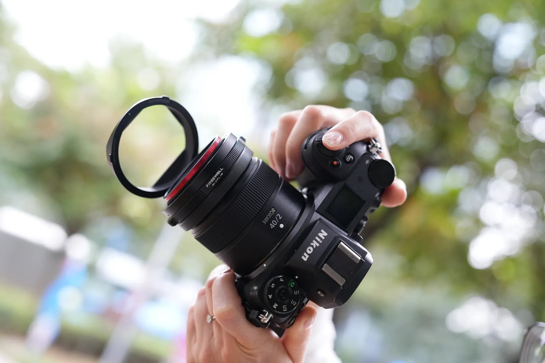 Photographer holding Nikon camera with the Real Lens Hood flipped open