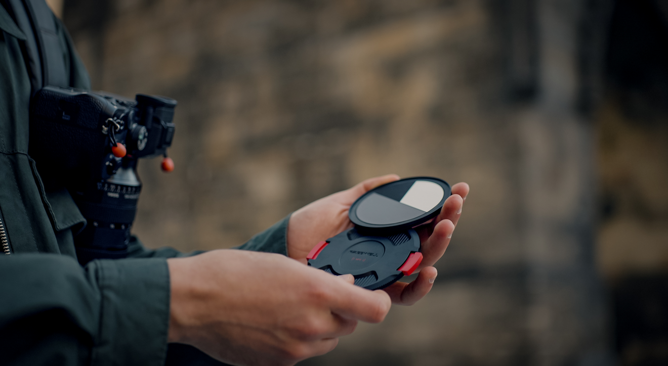 Person holding NFC lens cap and white balance back cap for real locking vnd cpl.