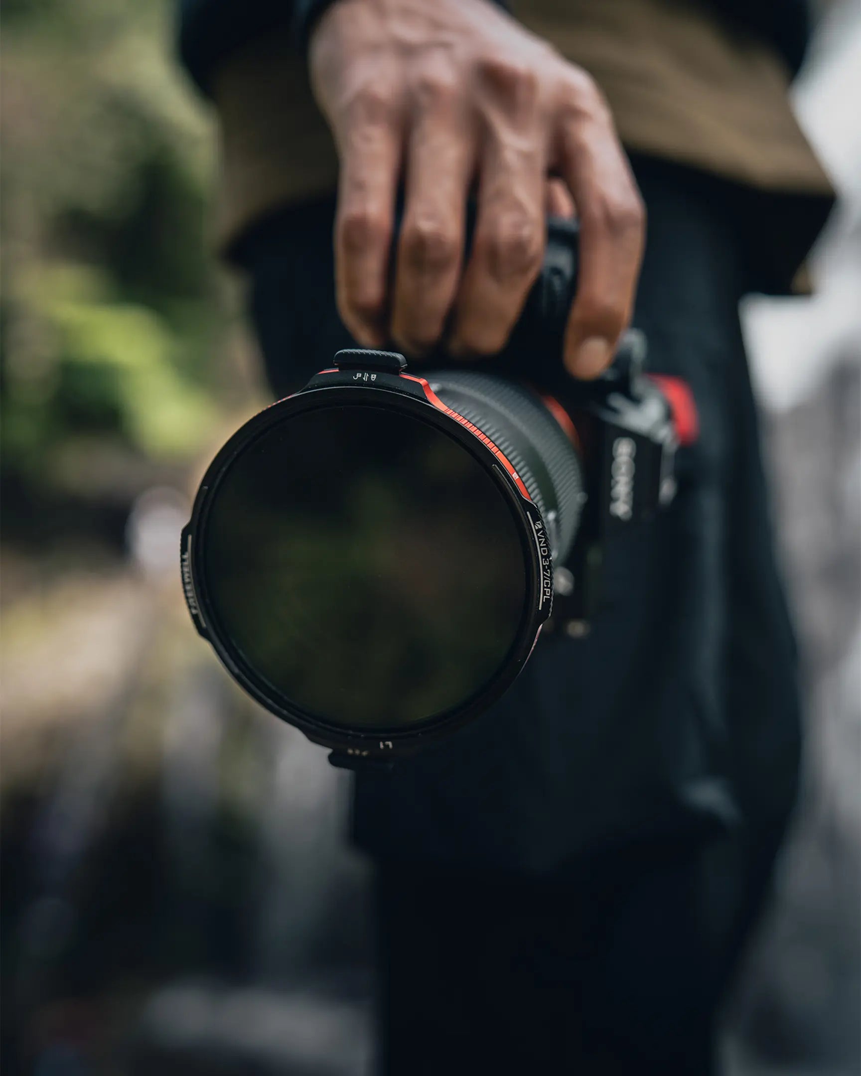 Creator holding a camera fitted with the Real Locking VND/CPL filter in a forest
