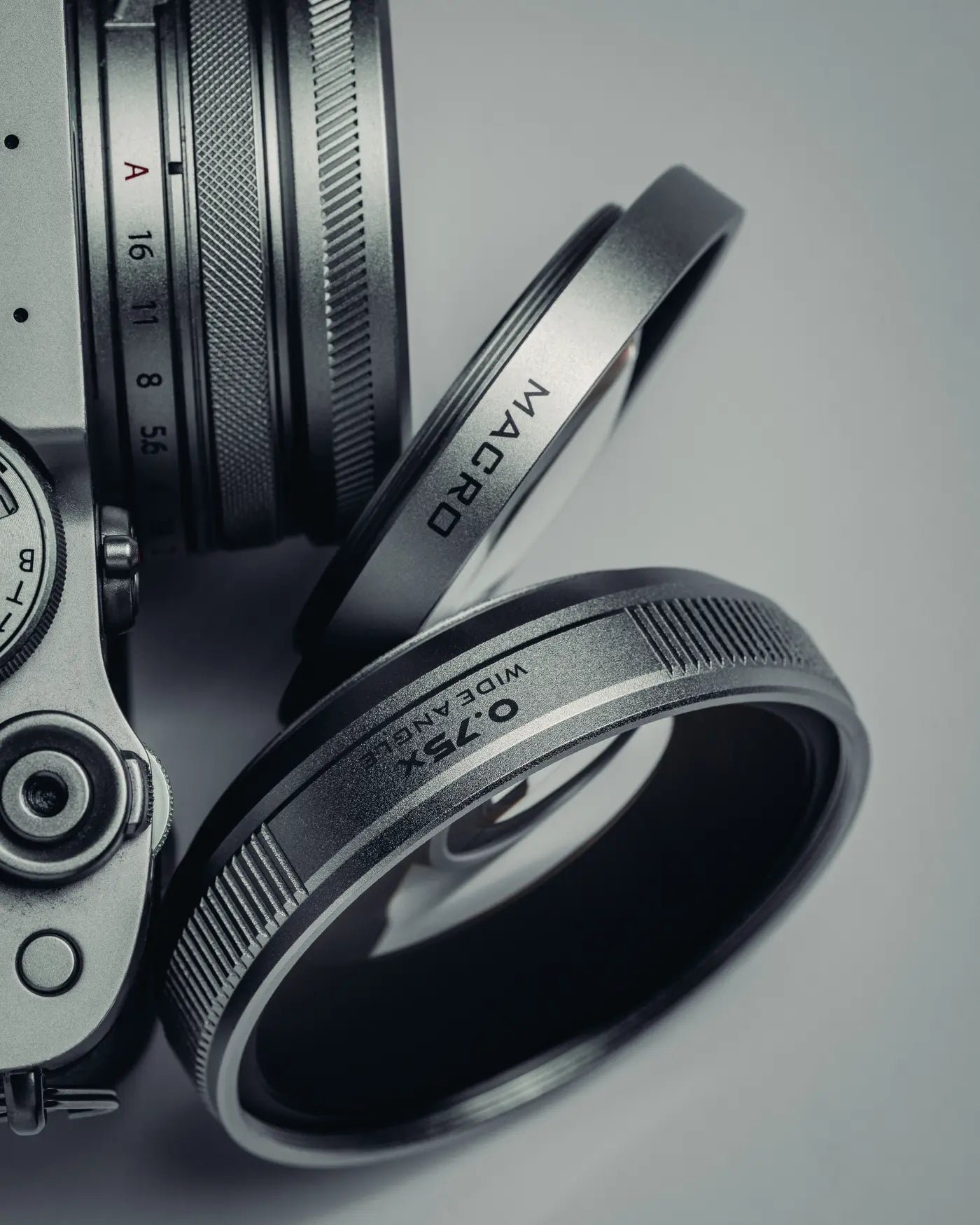Close-up editorial photograph of the Freewell macro and wide-angle elements beside a Fujifilm camera