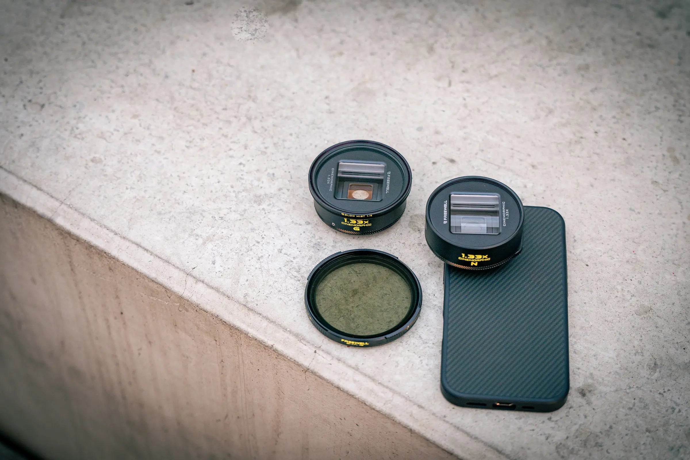 Freewell smartphone lenses and slide-on lens filter beside a phone