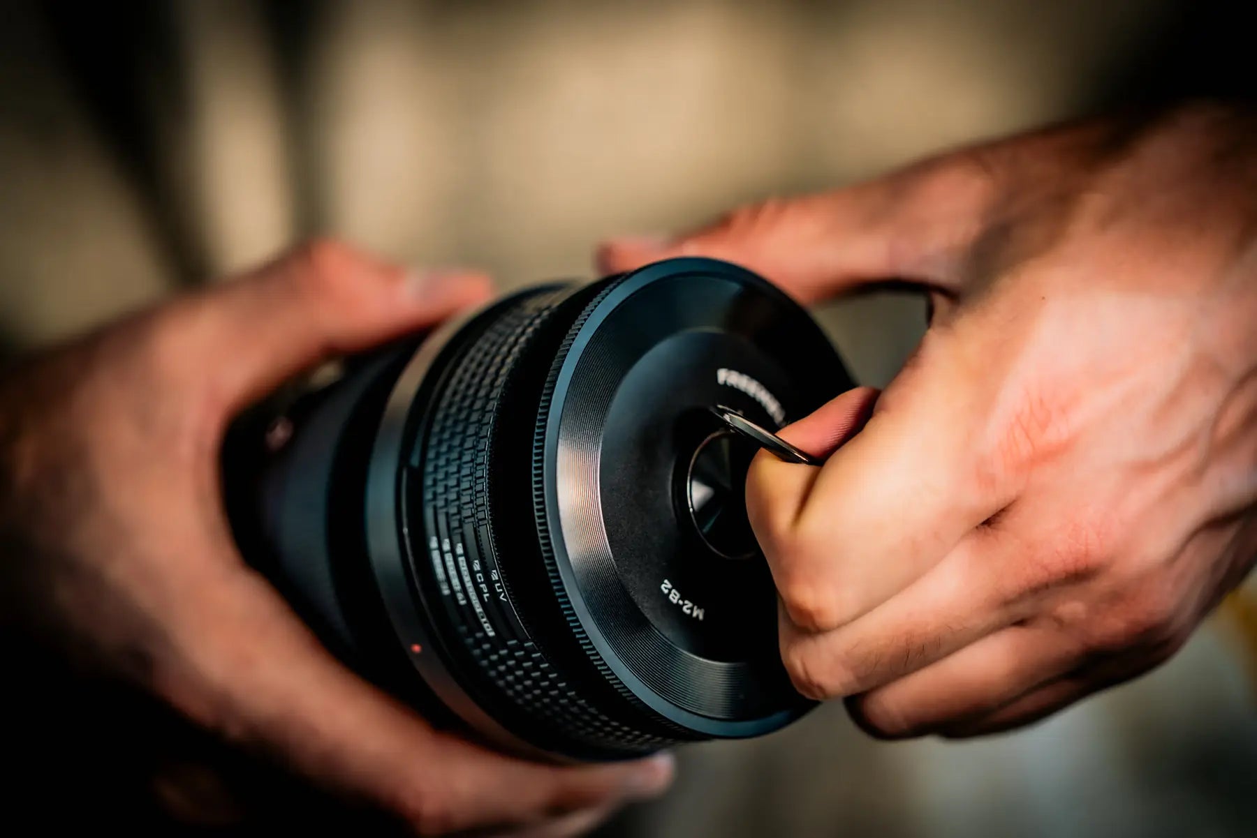 Hand using the pull holder on the M2 magnetic lens cap