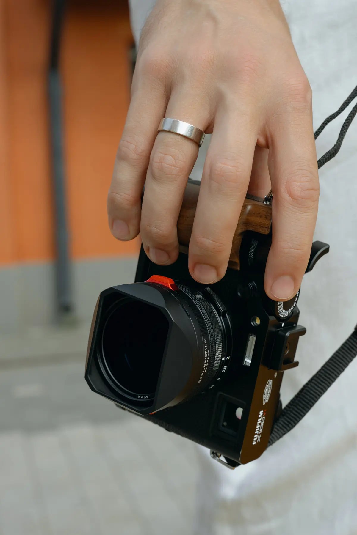 Fujifilm X100VI carried naturally in one hand with the thumb grip installed