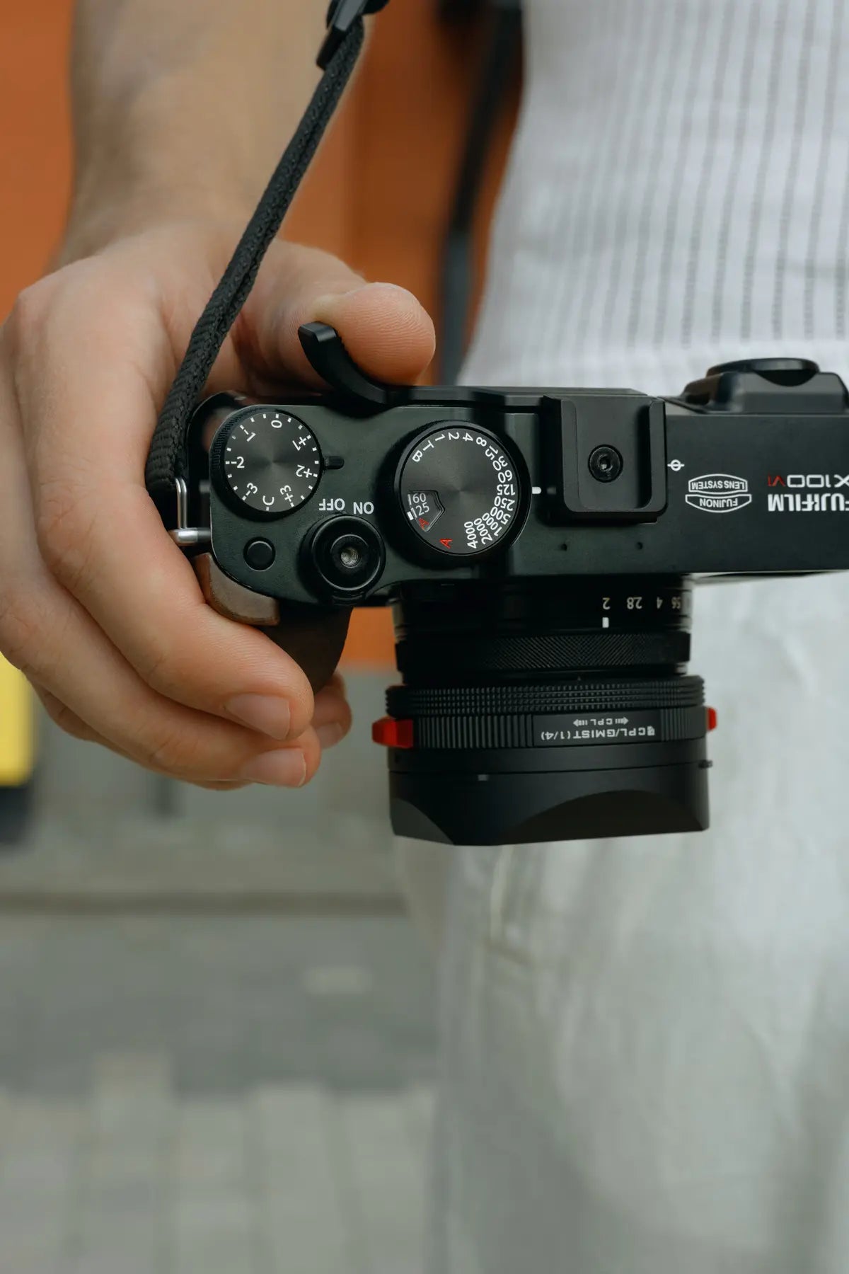 Photographer holding a Fujifilm X100VI with the Freewell thumb grip installed