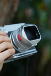 Hand holding a Fujifilm GFX100RF with Lens hood