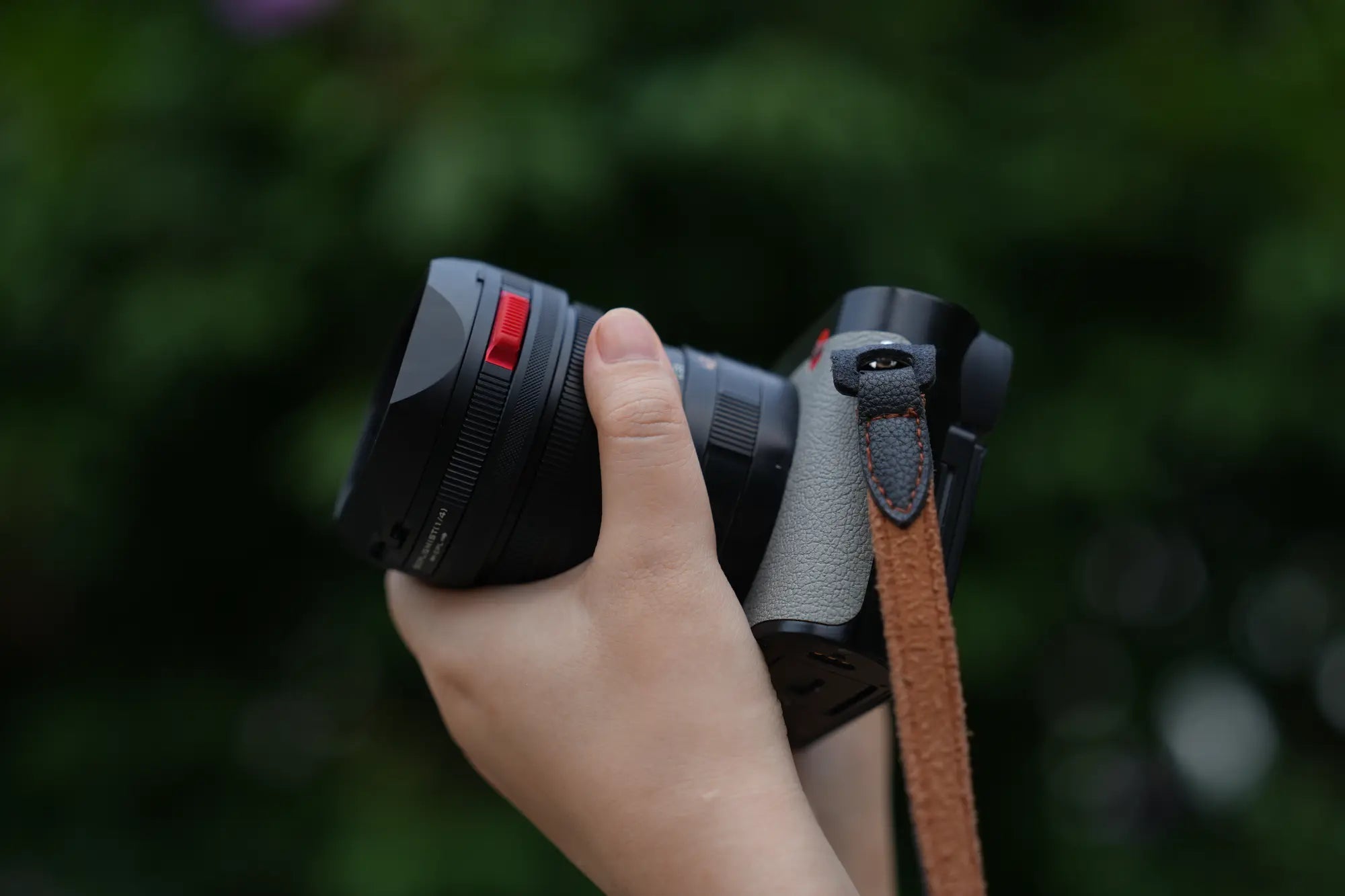 Leica Q3 43 held in one hand with the Freewell Real Lens Hood installed